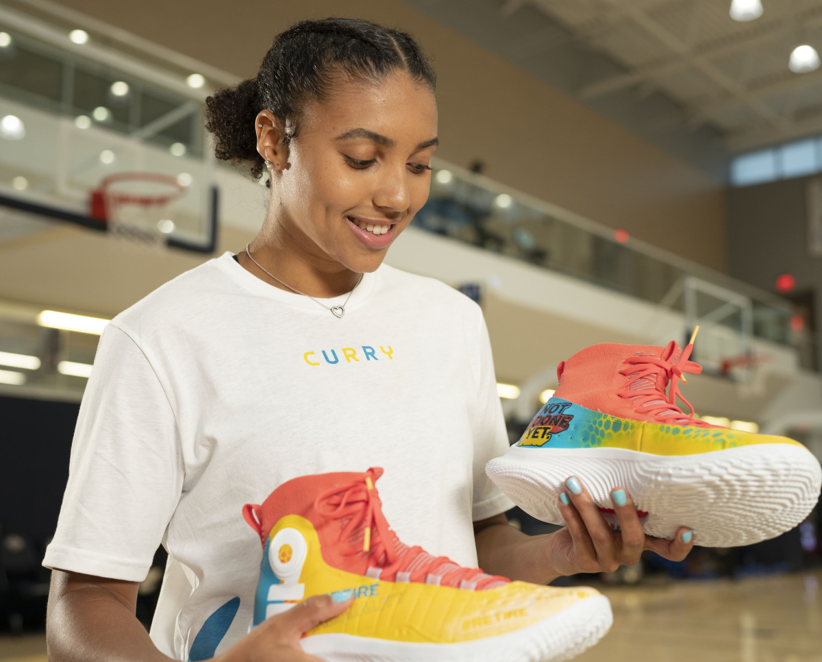 Azzi Fudd holds a pair of #RetireInequality custom shoes.